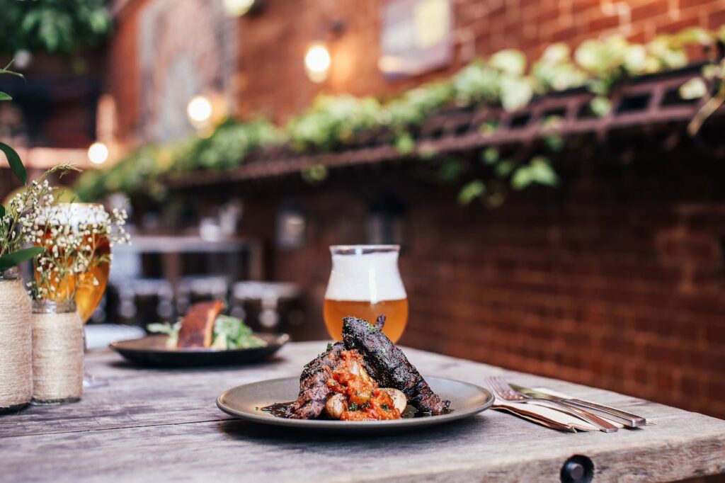 A delicious grilled meat dish served with beer in a cozy outdoor restaurant setting.